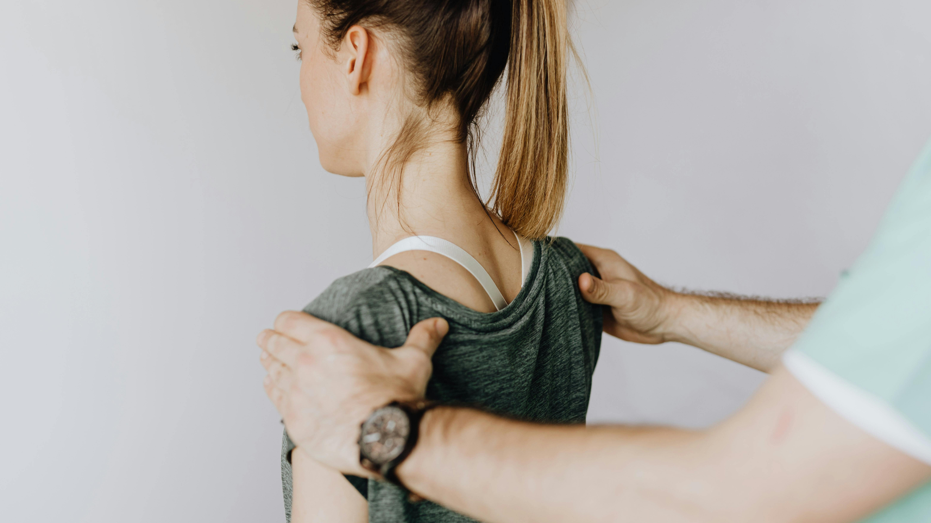 A woman wearing athletic attire working a physical therapist to help adjust her posture.